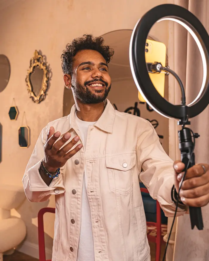 Man filming with a phone on a ring light stand