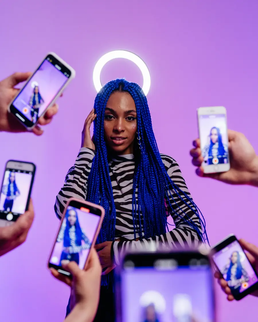 Creator lit by a ring light, surrounded by phones filming her